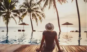 Person relaxing by an oceanfront infinity pool at sunset, representing luxury rehab and private addiction treatment.