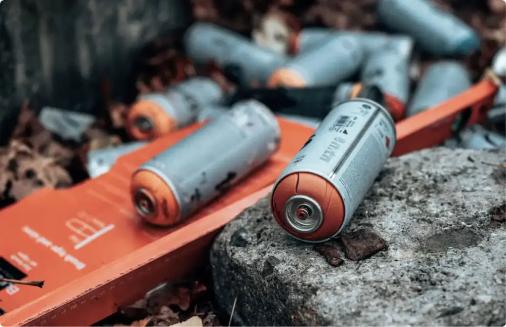 Discarded aerosol spray cans on the ground, representing inhalant substance misuse and the need for addiction treatment.