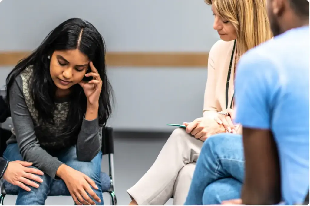 Woman in dual diagnosis group therapy session discussing co-occurring mental health and substance use disorder with counselor.