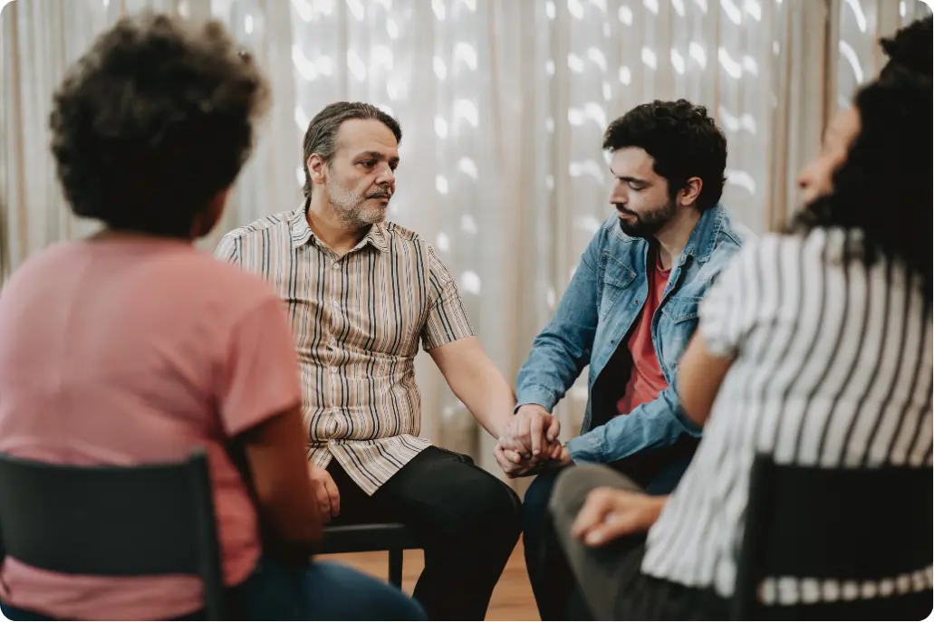 Participants holding hands during a group therapy session in an Intensive Outpatient Program (IOP)