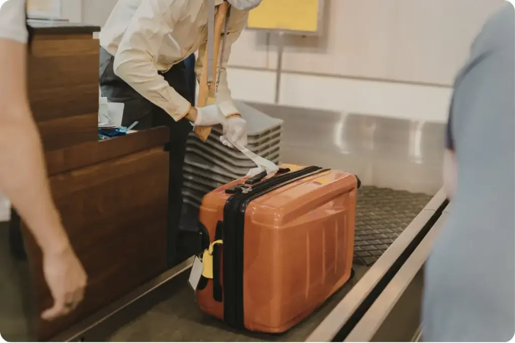 Airport staff member wearing gloves assisting with luggage as part of white-glove travel support for rehab clients