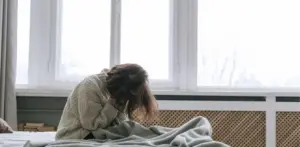 Person sitting on bed with head in hands showing depression linked to Xanax addiction