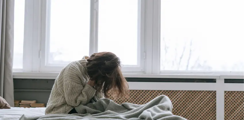 Person sitting on bed with head in hands showing depression linked to Xanax addiction
