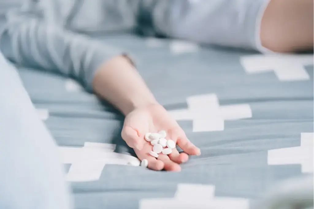 Person holding prescription pain pills illustrating the relationship between chronic pain, medication use, and addiction risk.